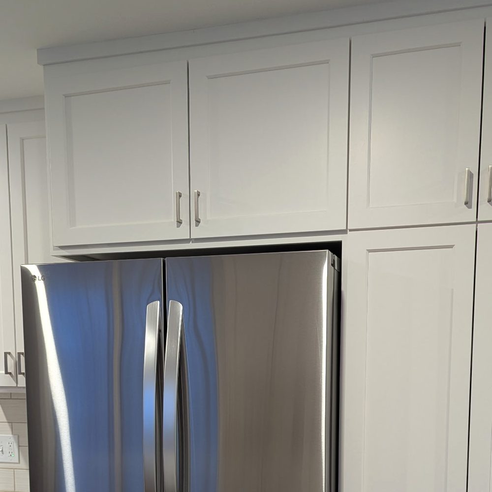 Close view of a cabinet built over a refrigerator, flush with the pantry beside it