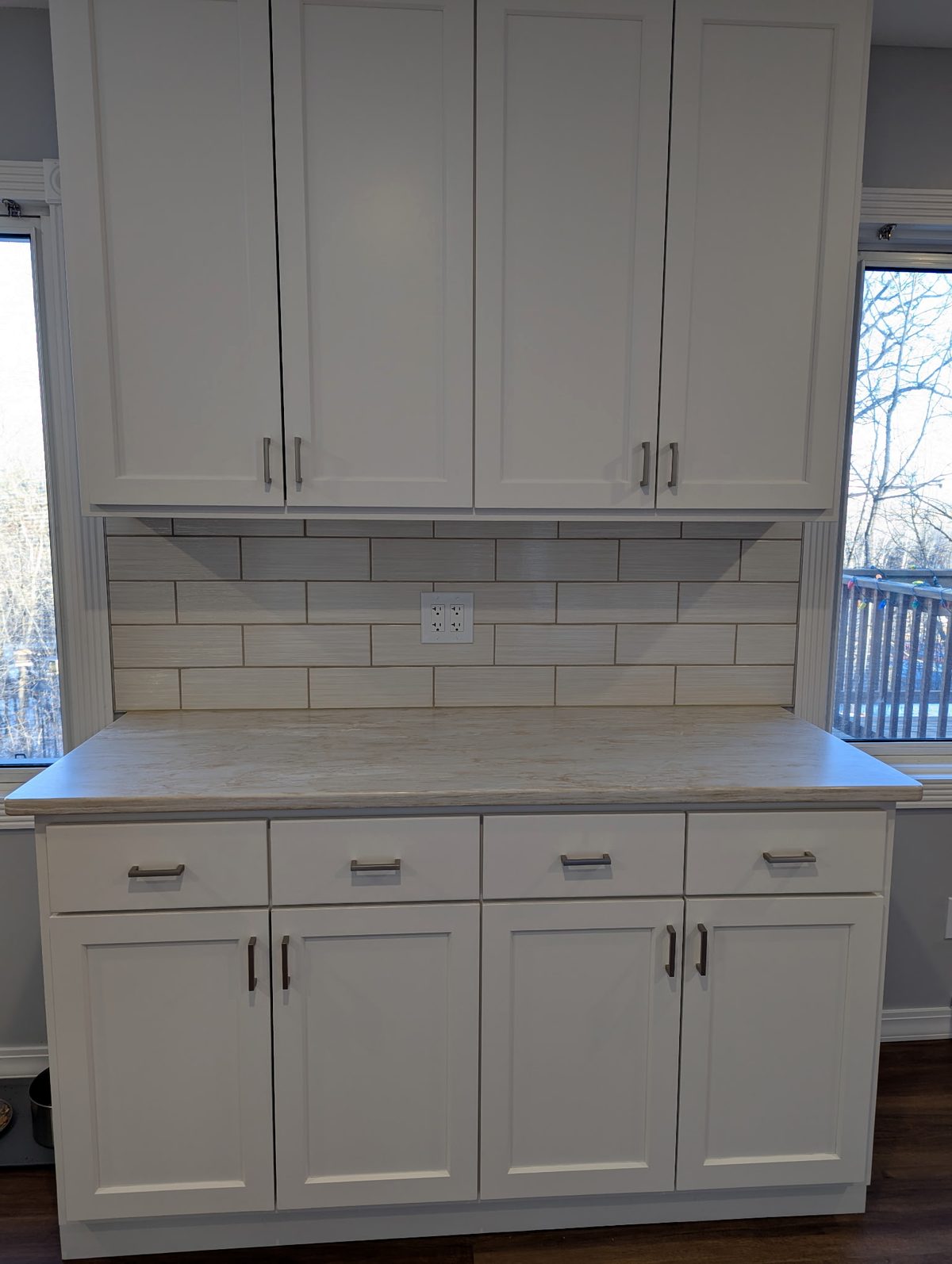 White shaker hutch with four upper doors, four drawers and four lower doors, fitted between two windows