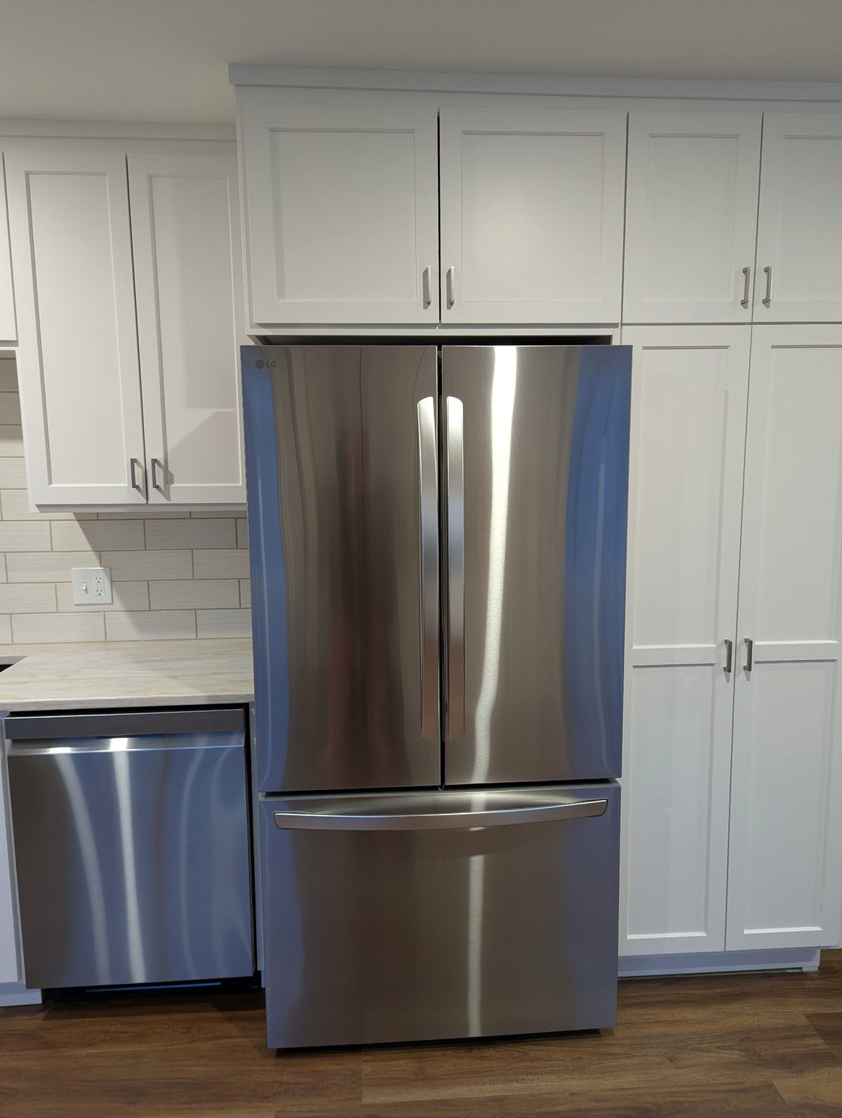 White shaker pantry wall with cabinets over the refrigerator, seen straight on